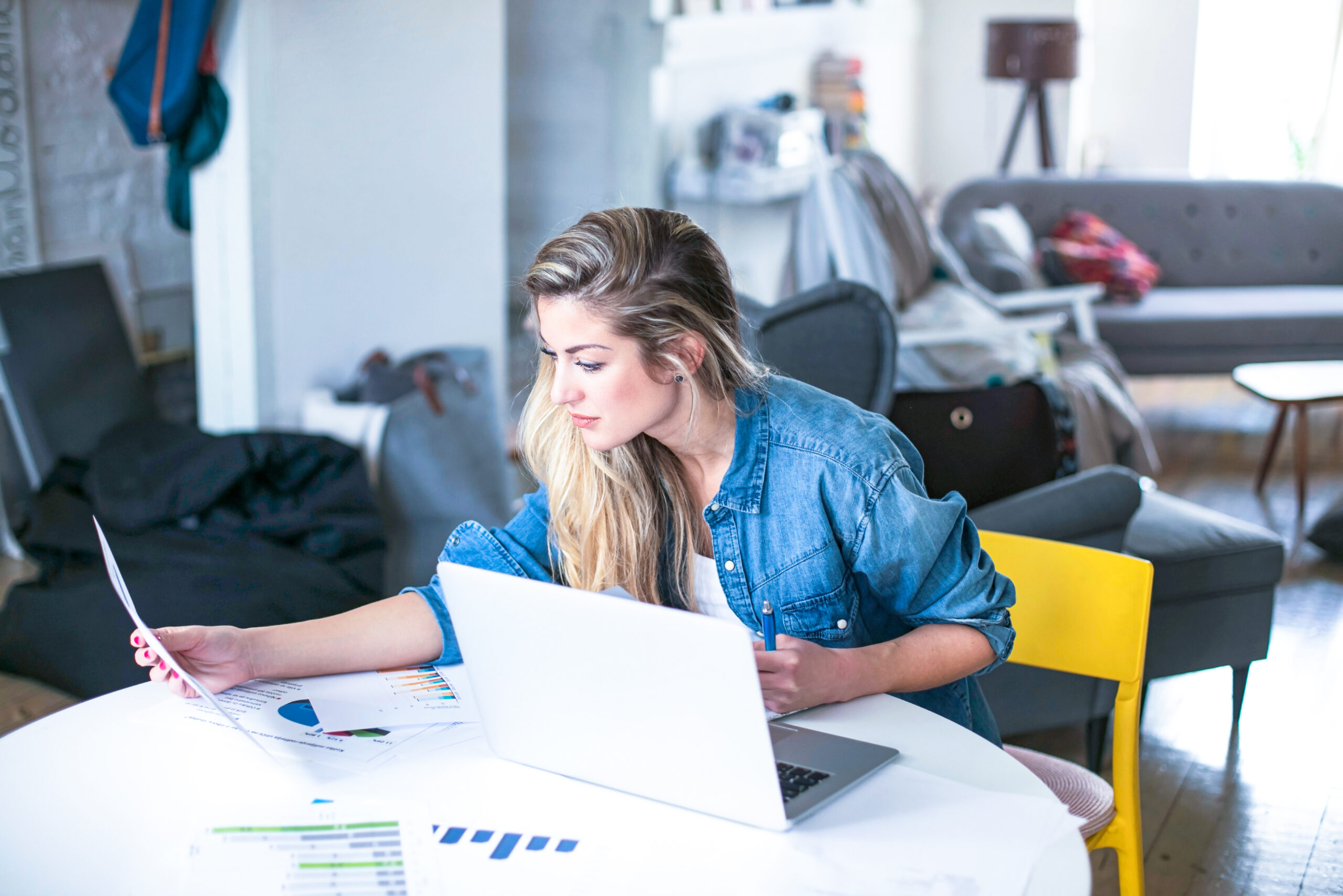 Vrouw aan tafel thuis aan het werk met laptop en papier